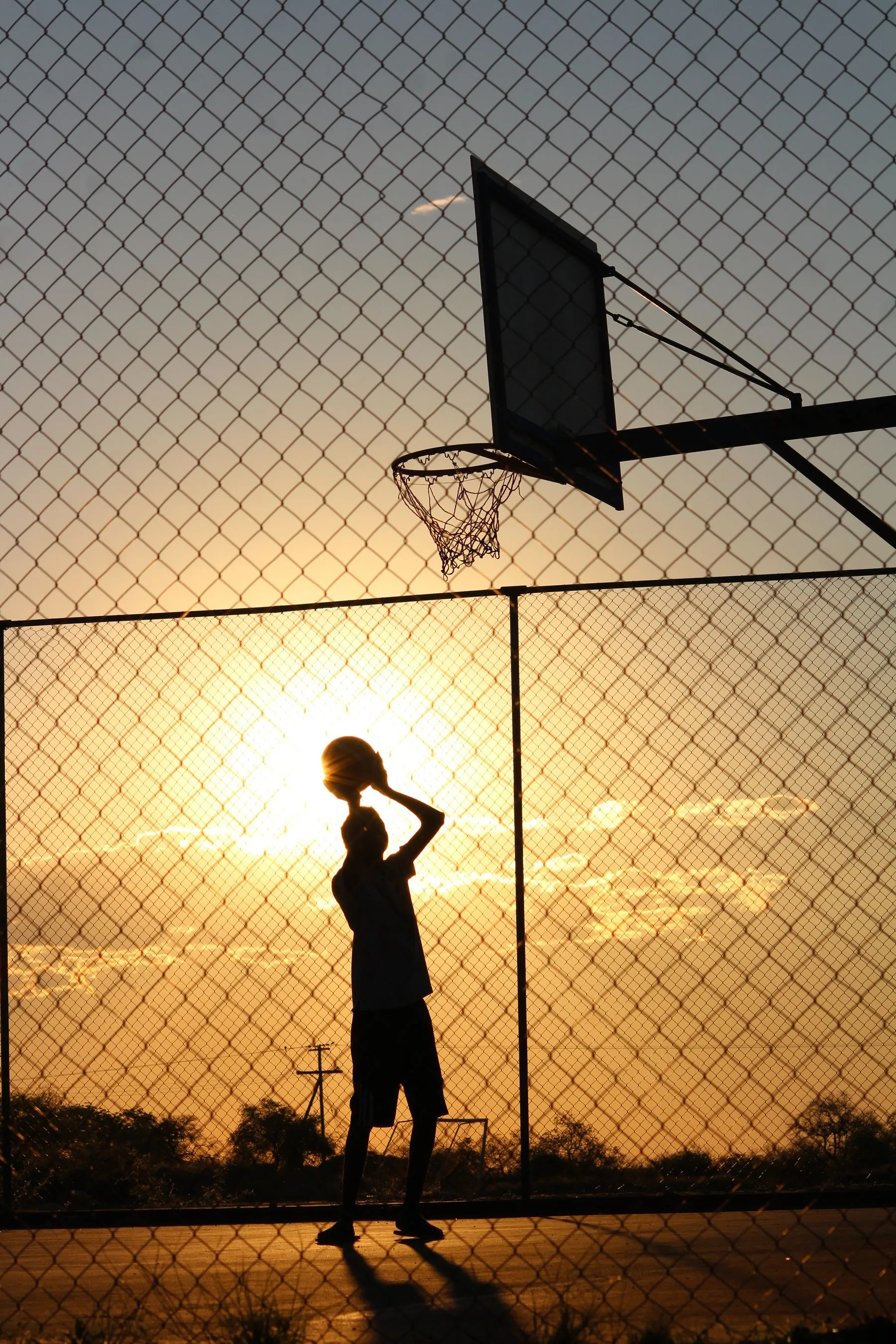 Young basketball player rising toward the hoop at golden hour